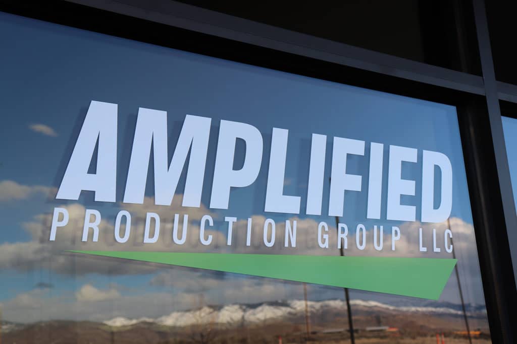Amplified Production Groups sign on a window featuring a green triangle.